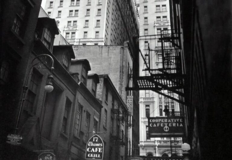 Rue d'une grande ville entre des immeubles anciens, en noir et blanc