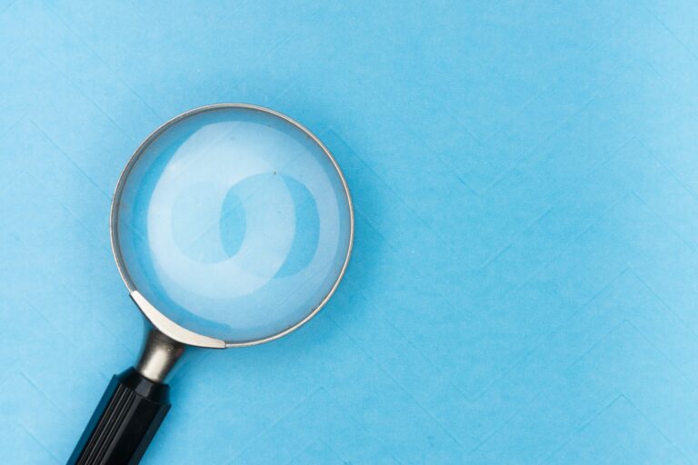 Une loupe posée sur un fond bleu clair