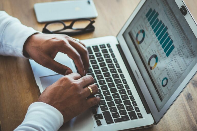 Mains tapant sur le clavier d'un ordinateur portable qui affiche des graphiques